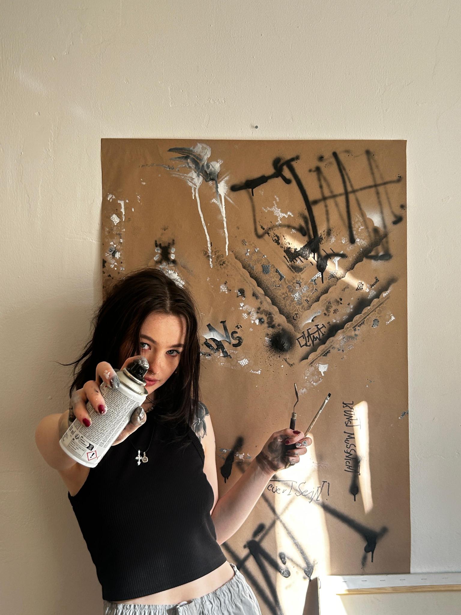 Die Künstlerin mit Spraydose und Pinsel vor einem Uptrashing-Kunstwerk